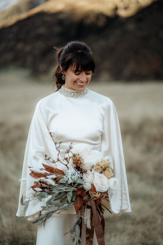 bride holding native floral bouquet in in brooke tyson ritual dress during glenorchy elopement